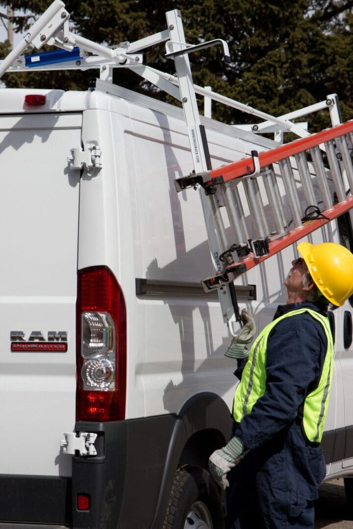 A man in yellow hard hat standing next to ladder truck.