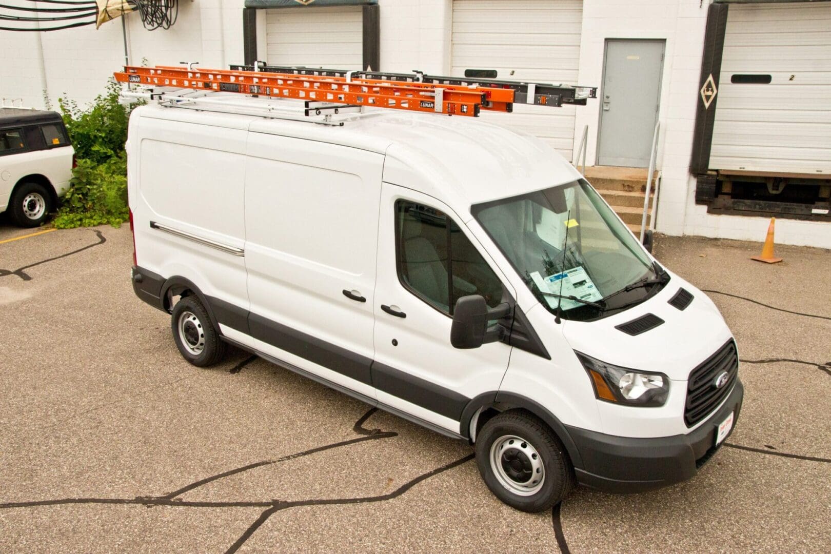 A white van with a ladder on the back of it.